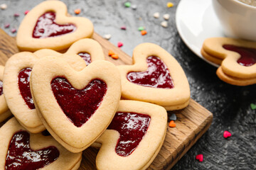 Board with tasty cookies for Valentine's Day celebration on dark background, closeup