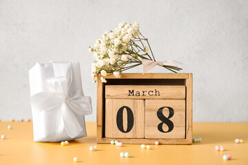 Wooden cube calendar with date MARCH 8, gift box and gypsophila flowers for International Women's Day celebration on light background