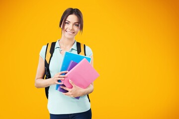 Smiling woman student with school books in hands on the background.