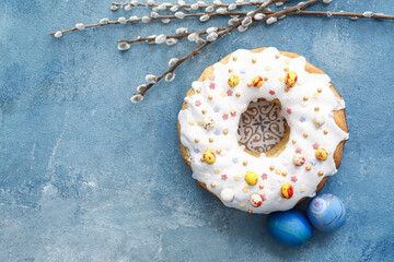Tasty Easter cake, pussy willow branches and eggs on blue background