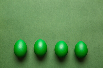 Green painted Easter eggs on color background