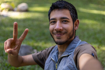 Self-portrait of Young Latin American adult (24) makes a positive waving gesture in front of his cell phone. Technology concept.