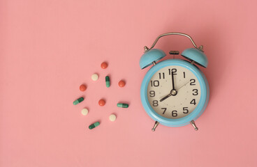 alarm clock on blue table with medication