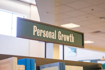 A view of a bookstore aisle and the genre sign for books on the subject of Personal Growth. 