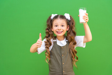 A glass of fresh milk in the hands of a beautiful girl, the child holds a glass of kefir and shows...