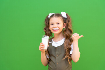 A delicious milkshake for breakfast in the hands of a cute kid. A girl with a cocktail points to an advertisement. The benefits of dairy products for the child's body.