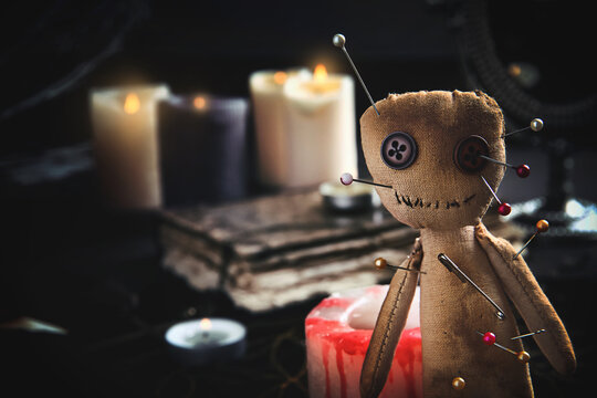 Voodoo doll pierced with pins on table indoors, closeup