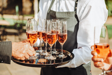 Pink champagne in glasses on a tray. Banquet in the open air. 