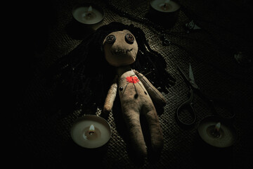 Voodoo doll with pins surrounded by ceremonial items on burlap fabric