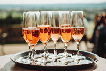Pink champagne in glasses on a tray. Banquet in the open air. 