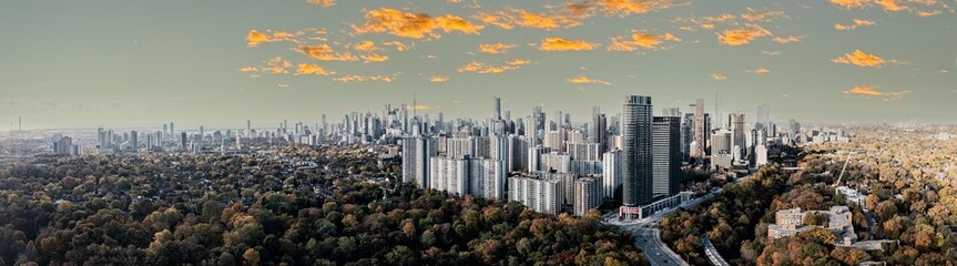 Fototapeta premium Drone Panorama of Toronto skyline with trees surrounding the cityscape sun set time 