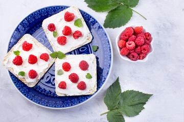 Toast with cream cheese and fresh raspberries on a blue plate. A delicious summer dish for breakfast.