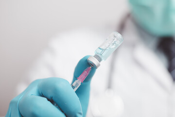 doctor or scientist in the COVID-19 medical vaccine research and development laboratory holds a syringe with a liquid vaccine to study and analyze antibody samples for the patient.
