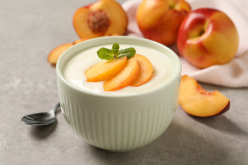 Delicious yogurt with fresh peach and mint on grey table, closeup