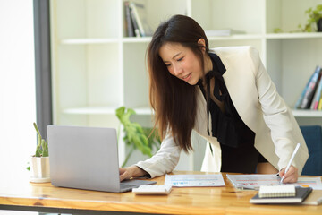 Businesswoman leaning on table and searching an informations on laptop.