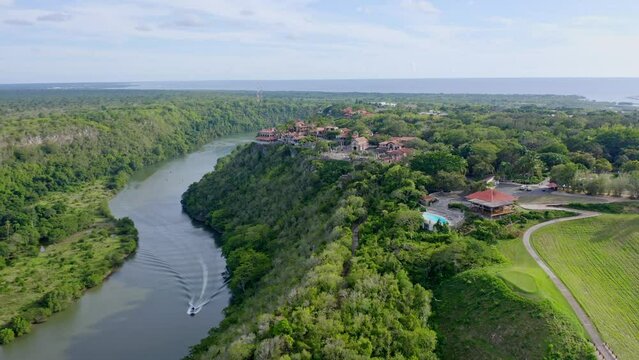 Aerial shot backwards in alto de chavon la romana, overlooking the chavon river, vacationers sailing on a lacha on a sunny day