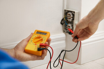 Electrician with tester checking voltage indoors, closeup