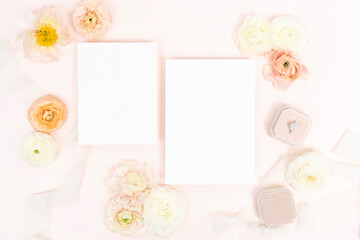 Fototapeta na wymiar Beautiful floral flat lay with blank wedding stationery on blush background with fresh flowers