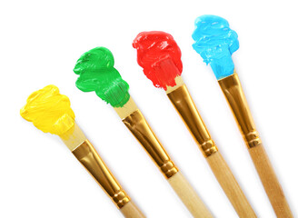 Brushes with colorful paints and strokes on white background, top view
