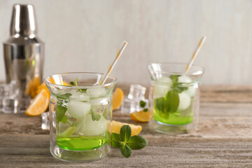 Delicious cocktails with mint and ice balls on wooden table