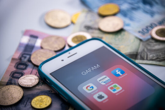 Kumamoto, Japan - May 29 2020 : GAFAM on iPhone with coins & bills..Google, Amazon, Facebook, Apple & Microsoft are 5 US multinational IT or online service companies dominated cyberspace during 2010s