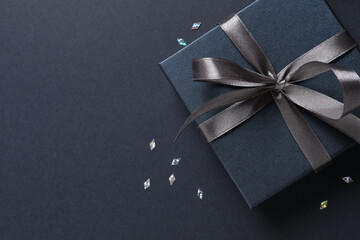 Beautiful gift box and confetti on black background, flat lay. Space for text