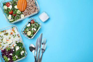 Set of glass containers with fresh food and cutlery on light blue background, flat lay. Space for...