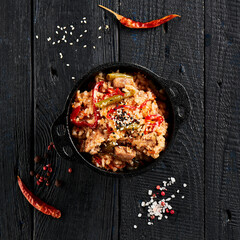 Chicken fried rice on wok. Asian food - fried rice with vegetables, egg and chicken on dark table. Wok menu on black wood background. Traditional chinese food.