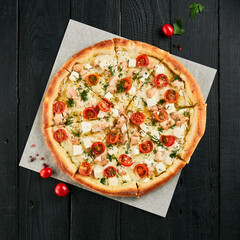 Homemade salmon pizza on black wood background.  Pizza with salmon, tomatoes, dill and feta cheese...