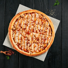 Homemade chicken pizza on black wood background.  American pizza with chicken and sweet and sour sauce. Modern italian food. Junk food on dark background.