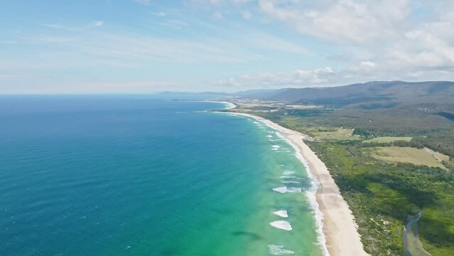 Stunning high angle aerial panoramic drone footage of Lagoons Beach Conservation Area and the A3 Tasman Highway near the village of Scamander on the east coast of Tasmania, Australia on a sunny day.