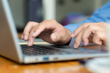 press the computer keyboard side view Close-up shots and focus on a specific point on the finger man using the laptop to work on the desk in an office