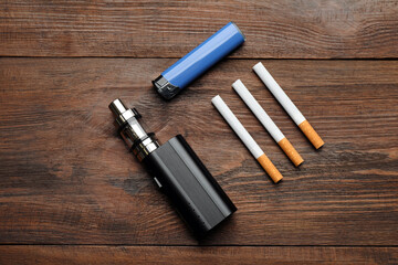 Cigarettes, lighter and vaping device on wooden background, flat lay. Smoking alternative