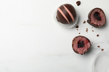 Different delicious chocolate truffles on white marble table, flat lay. Space for text