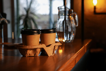 Paper coffee cups on wooden table in cafe. Space for text