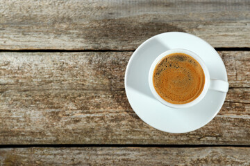 Cup of tasty coffee on wooden table, top view. Space for text