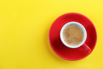 Cup of tasty coffee on yellow background, top view. Space for text