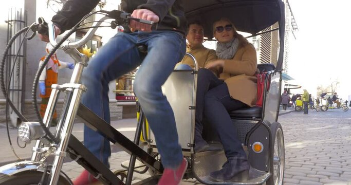 Couple riding in bicycle taxi and talking to each other