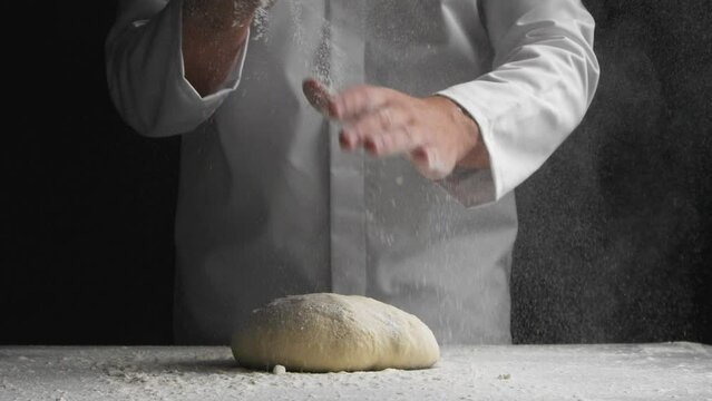 Baker throwing flour over bread dough before kneading