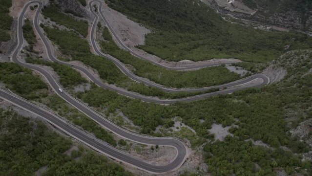 Drone video of descriptive panning over the "Rrapsh Serpentine" mountain pass on the Sh20 road in Grabom,Albania, you can see a motorcycle  and car passing by.
Leqet e Hotit