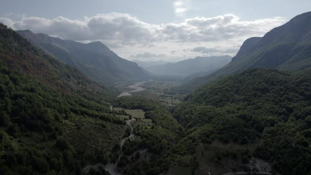 Drone video of frontal plane advancing over the Vermosh valley above the Vermoshi river, the sh20 at the height of Bashkimi, Albania. you can see small houses of the town.