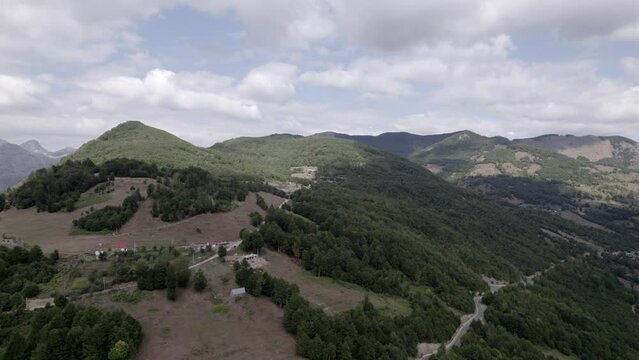 Video with descriptive panning Drone advancing on the Sh20 road in the Lepush&euml; valley in Albania, small houses of the town can be seen, somewhat cloudy sky.