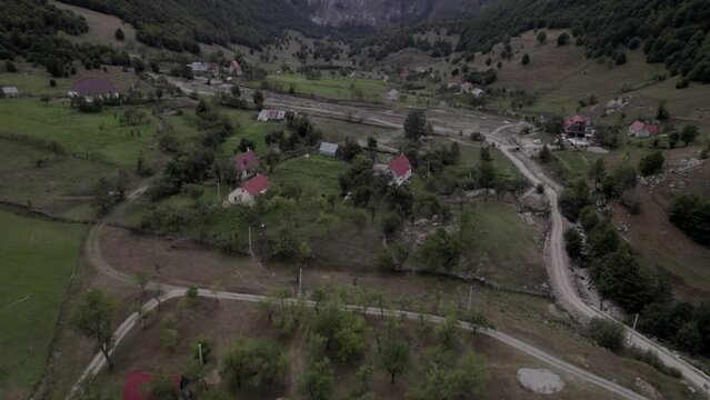 Video with descriptive panning Drone advancing over the Lepush&euml; valley above the L&euml;pusha river, the sh20 in Albania, you can see small houses of the town, somewhat cloudy sky and the dry river.
