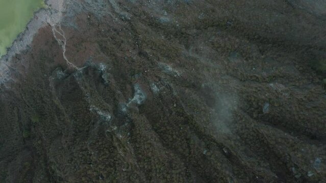 Aerial flyover scenic volcano landscape after eruption showing hills and pattern beside crater lake