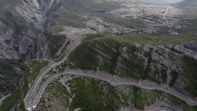 Drone video of a revealing "tilt" plane from a bird's eye view over the Rrapsh Serpentine" mountain pass on the Sh20 road in Grabom Albania  Leqet and Hotit can be seen circulating vehicles