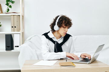 curly guy laptop in headphones on white sofa Lifestyle technology