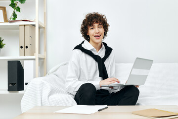 curly guy on a white sofa in front of a laptop learning living room