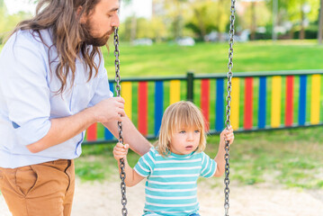 A young man playing with his adopted son on swing