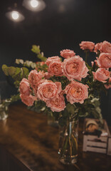 Pink rose in a glass vase on a wooden table in a flower shop. Showcase. Background from a mixture of colors. Beautiful flowers for a catalog or an online store. Flower shop and delivery con