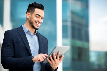 Successful arab guy in formal wear using digital tablet